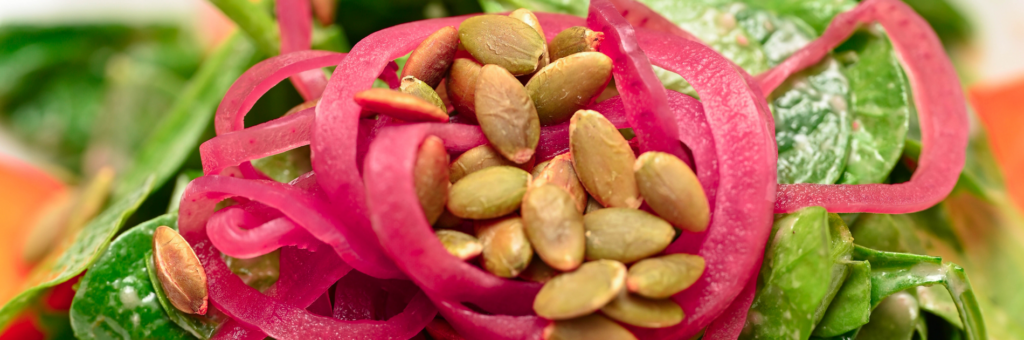 French culinary techniques enhance menu items like this close up of a spinach salad with pickled onions